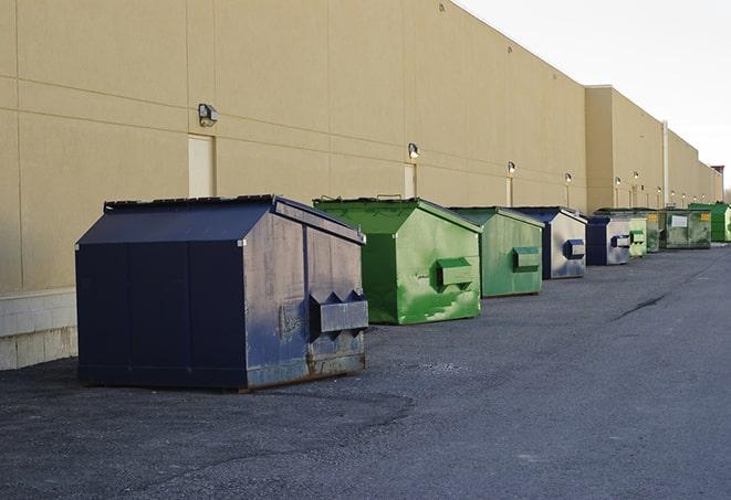 tilted front-load dumpsters being emptied by waste management workers in Aston